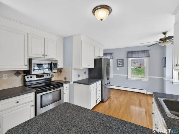 a kitchen with granite countertop a stove and a wooden floors