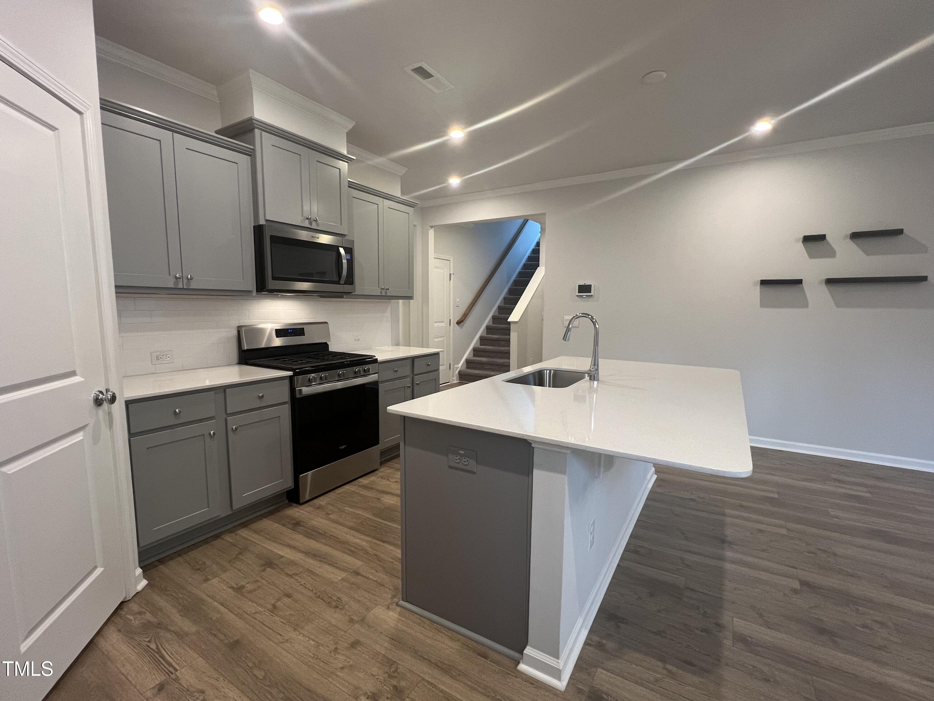 117 Clear Water Road Louisburg, NC 27549 - Photo 12 of 34 a kitchen with stainless steel appliances a sink dishwasher a microwave oven and a refrigerator with wooden floor