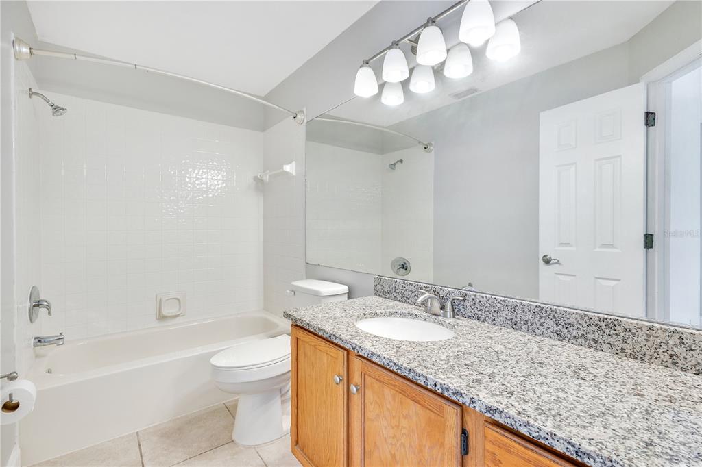 955 Forest Ridge Court, Unit 203 Lake Mary, FL 32746 - Photo 18 of 26 a bathroom with a granite countertop sink a toilet a mirror a bathtub and shower