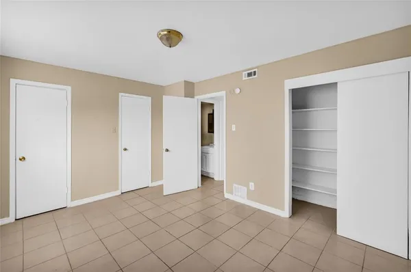 a view of an empty room with bathroom and window