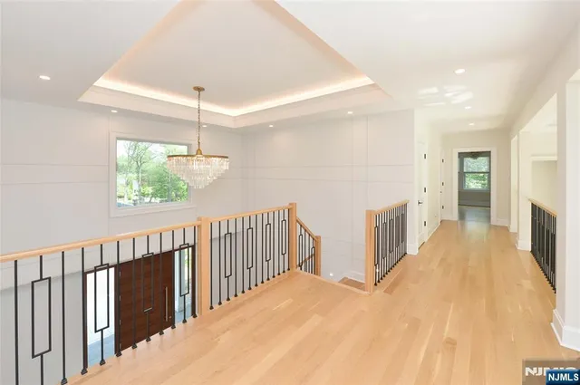 a view of a hallway with wooden floor and chandelier