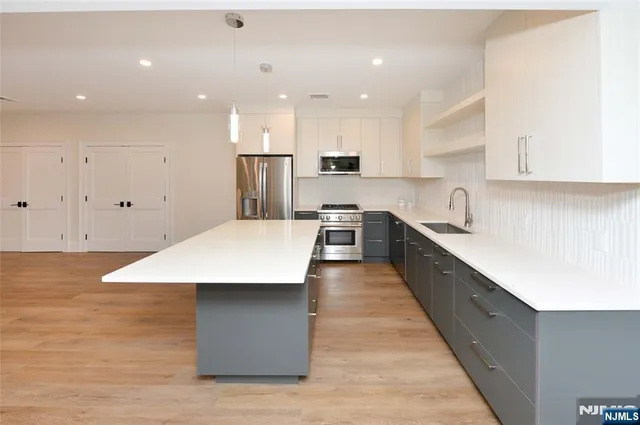 a large kitchen with kitchen island a sink a stove and a refrigerator