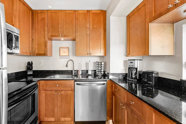 a kitchen with stainless steel appliances granite countertop a stove a sink a microwave and cabinets