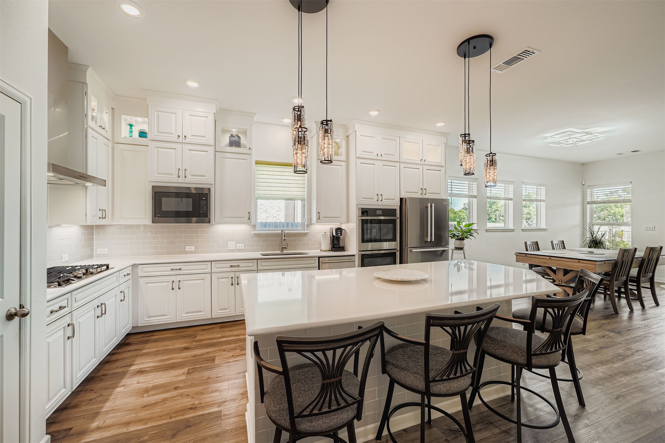1102 Simmental Loop Hutto, TX 78634 - Photo 5 of 29 a kitchen with stainless steel appliances kitchen island granite countertop a dining table chairs stove and white cabinets
