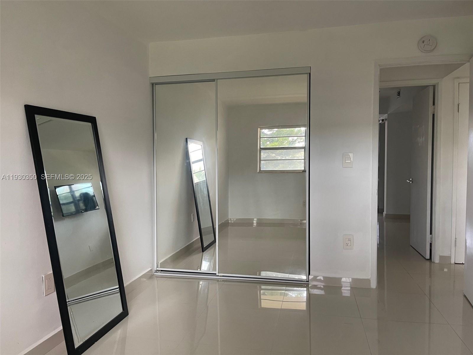 1670 Northeast 191st Street, Unit 2133 Miami, FL 33179 - Photo 12 of 15 a view of a livingroom with wooden floor and a mirror