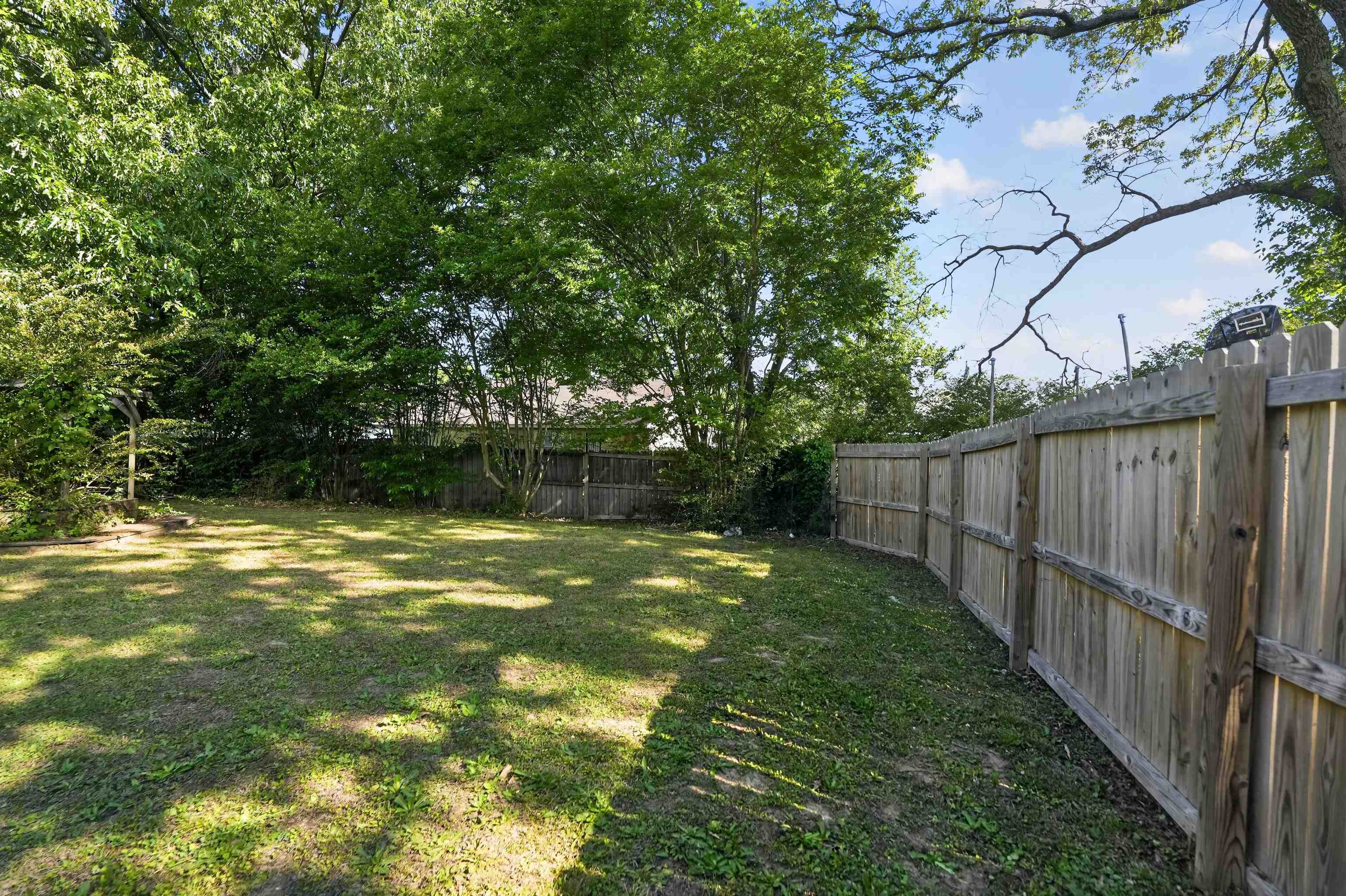 3372 Spring Shadow Drive Memphis, TN 38118 - Photo 2 of 35 Expansive backyard featuring a lush lawn, mature trees, and a perimeter wood privacy fence