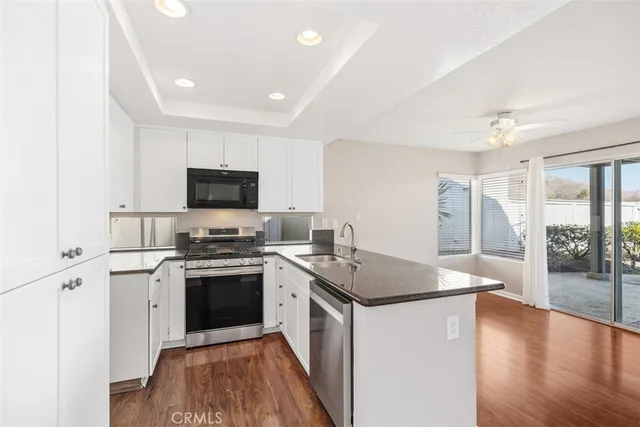 a kitchen with stainless steel appliances granite countertop a refrigerator a sink dishwasher a stove top oven a counter space and cabinets