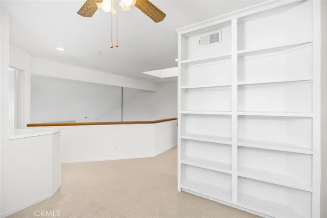 an empty room with a chandelier fan and windows