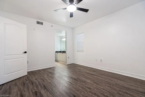 an empty room with wooden floor ceiling fan and windows