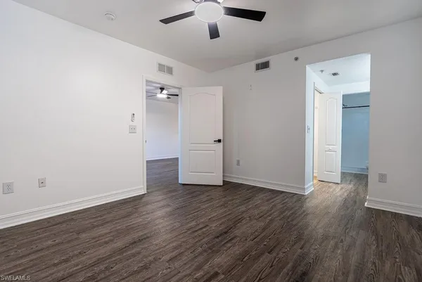 an empty room with wooden floor cabinet and windows
