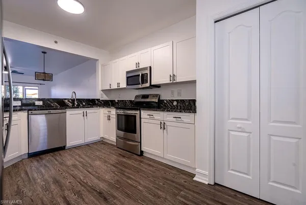 a kitchen with granite countertop white cabinets and white appliances