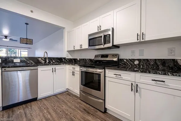a white kitchen with granite countertop stainless steel appliances