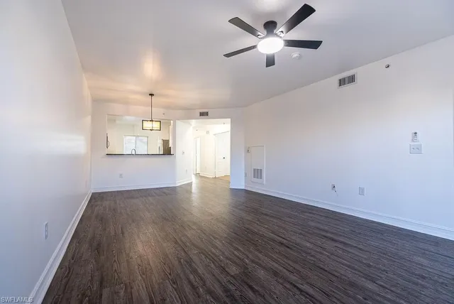 a view of an empty room with a window and wooden floor
