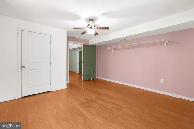 wooden floor in an empty room with a chandelier fan
