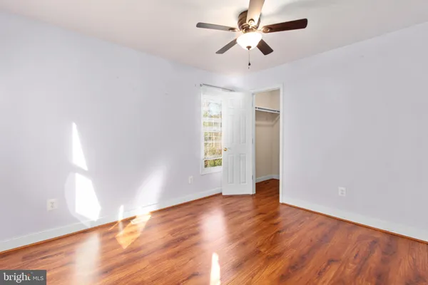 a view of empty room with wooden floor and fan