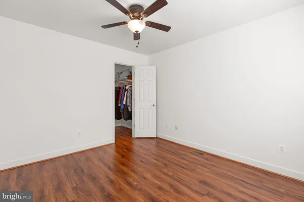 an empty room with wooden floor chandelier fan and closet area