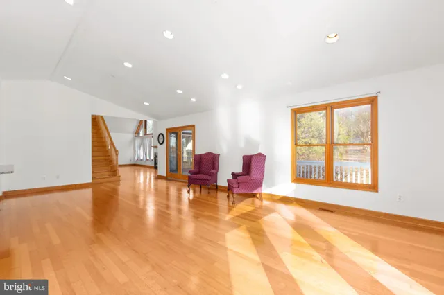 a view of an empty room with window and a kitchen view