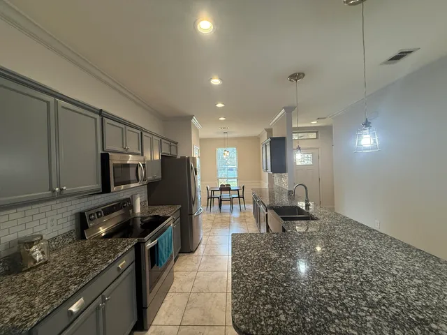 a large kitchen with stainless steel appliances granite countertop a sink stove and refrigerator