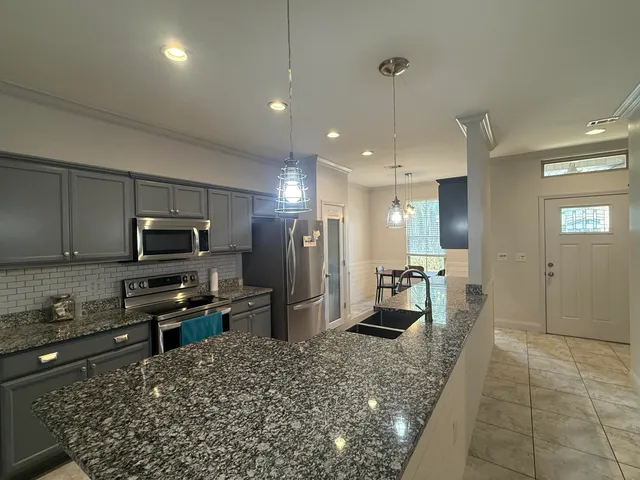 a kitchen with stainless steel appliances kitchen island granite countertop a refrigerator and a stove top oven