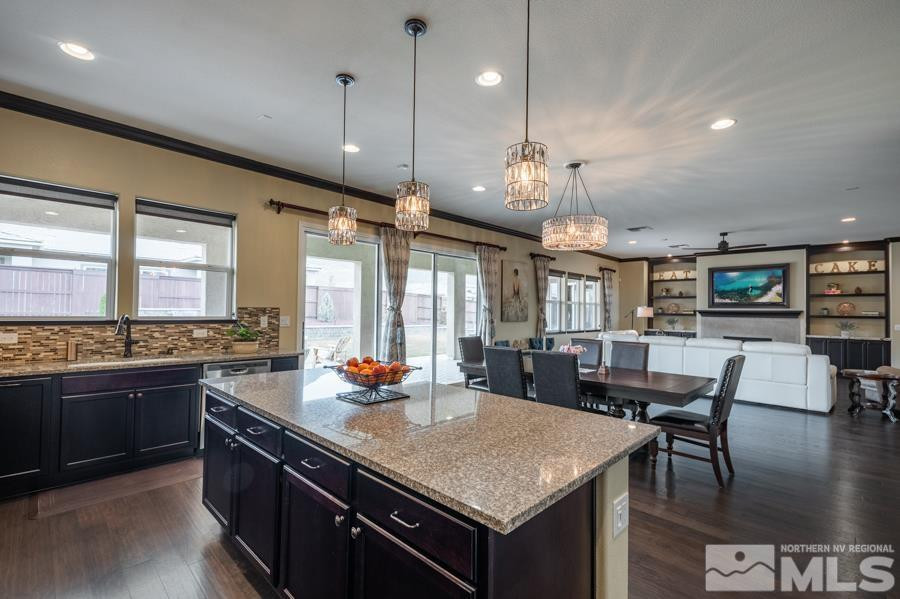9898 Firefoot Lane Reno, NV 89521 - Photo 12 of 40 a kitchen with a stove a kitchen island a dining table and chairs with wooden floor