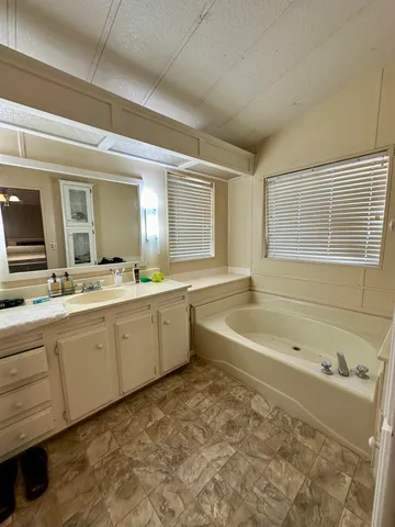 a spacious bathroom with a tub sink and mirror