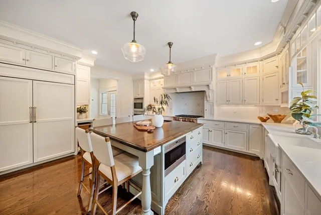 a kitchen with a stove a sink a kitchen island with chairs and wooden floor
