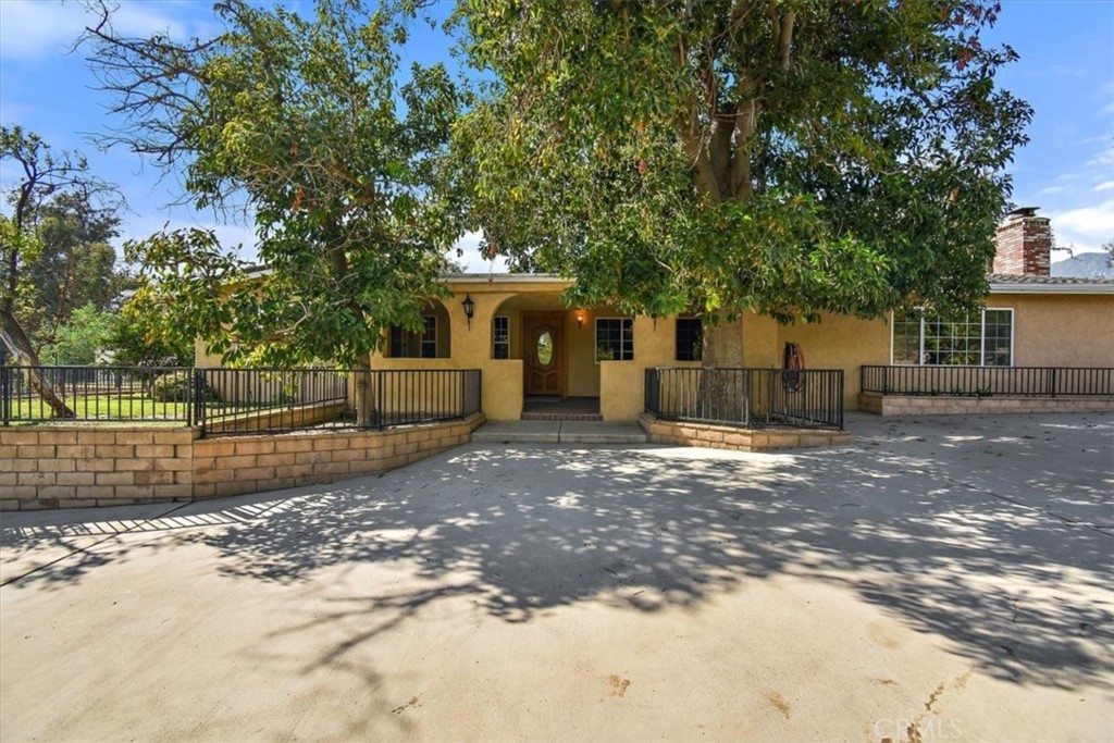 6060 Summit Lane Rancho Cucamonga, CA 91739 - Photo 1 of 1 a view of a white house with a large tree and wooden fence