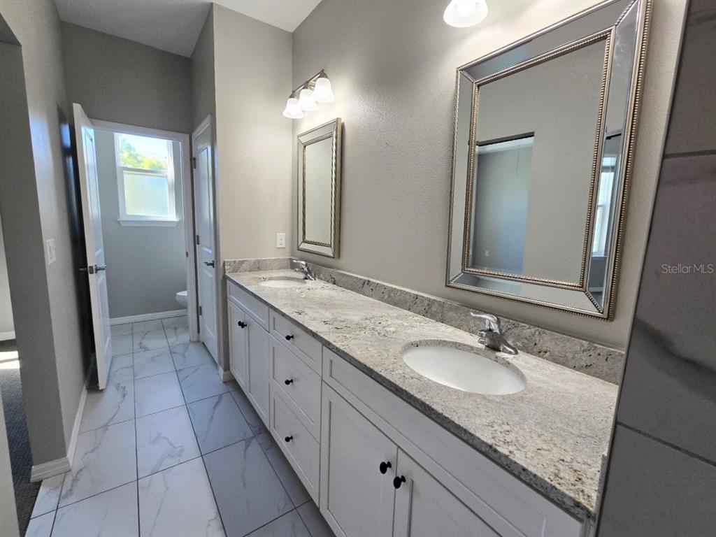 807 Callista Cay Loop Tarpon Springs, FL 34689 - Photo 19 of 32 a bathroom with a granite countertop double vanity sink and a mirror