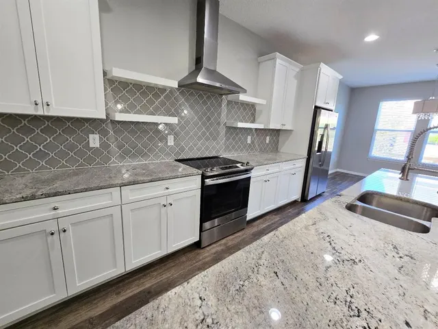 a kitchen with stainless steel appliances granite countertop a sink a stove and a wooden floors