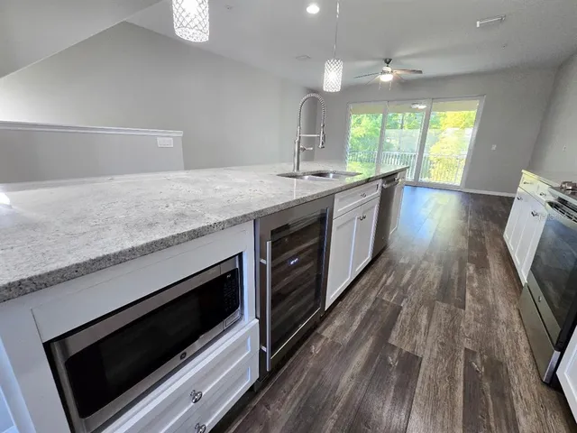 a kitchen with stainless steel appliances granite countertop a refrigerator a stove and a wooden floors