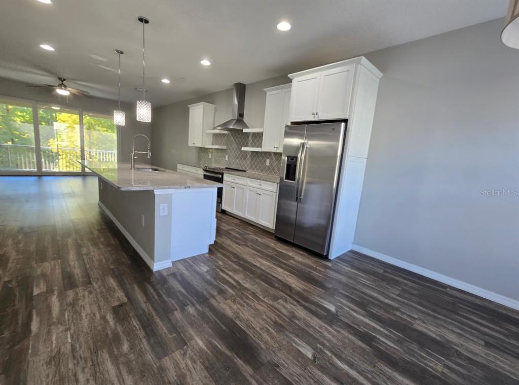 807 Callista Cay Loop Tarpon Springs, FL 34689 - Photo 9 of 32 a kitchen with stainless steel appliances granite countertop a refrigerator a stove and a wooden floors