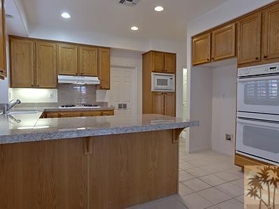 5 White Sun Way Rancho Mirage, CA 92270 - Photo 9 of 24 a kitchen with stainless steel appliances granite countertop a refrigerator a stove and a sink with wooden cabinets