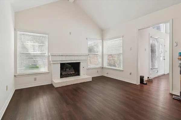 an empty room with wooden floor a fireplace and windows