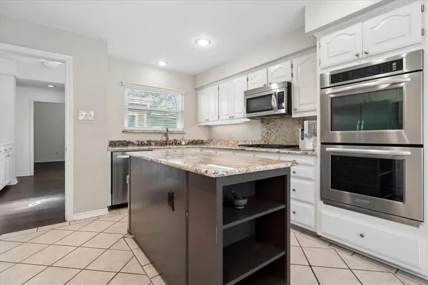 a kitchen with kitchen island granite countertop a stove top oven and sink