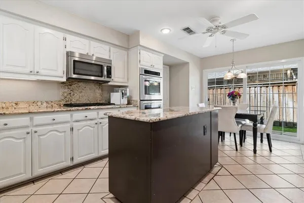 a kitchen with kitchen island granite countertop a sink cabinets and stainless steel appliances