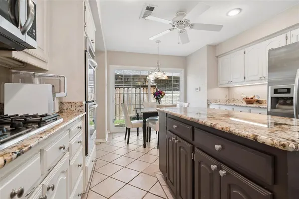 a kitchen with stainless steel appliances granite countertop a stove a sink dishwasher and a refrigerator with wooden floor