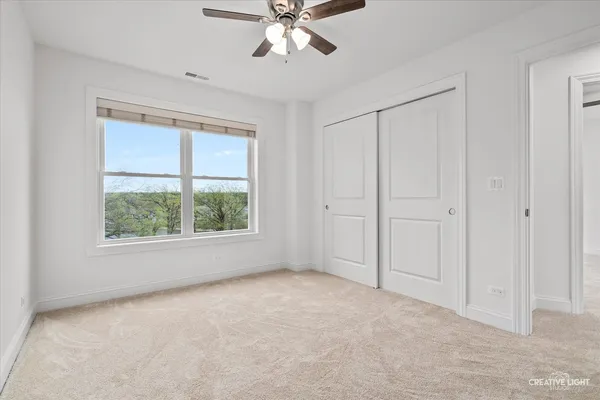 an empty room with chandelier fan and windows