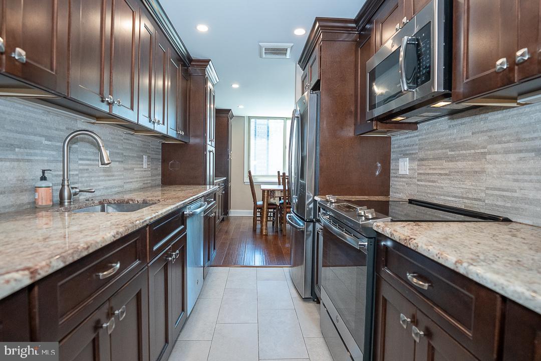 1919 Chestnut Street, Unit 807 Philadelphia, PA 19103 - Photo 5 of 25 a kitchen with granite countertop stainless steel appliances and wooden cabinets