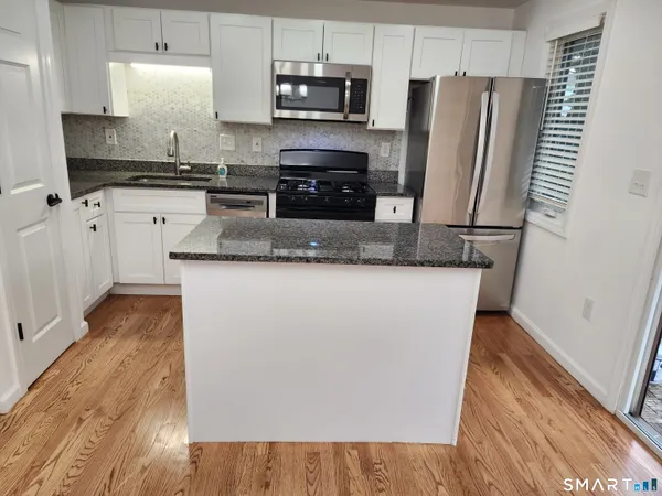 a kitchen with stainless steel appliances granite countertop a stove a sink and a microwave
