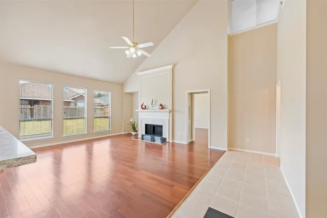 an empty room with wooden floor fireplace and windows