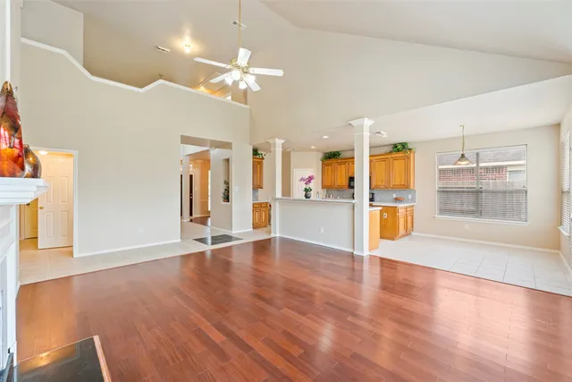 a view of an empty room with wooden floor and a kitchen