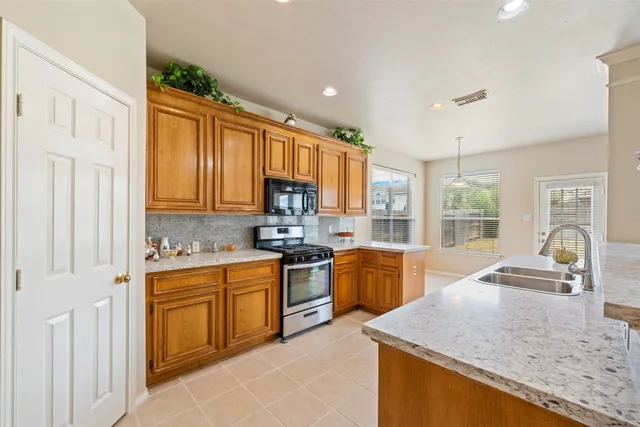 a kitchen with stainless steel appliances granite countertop sink stove top oven and cabinets