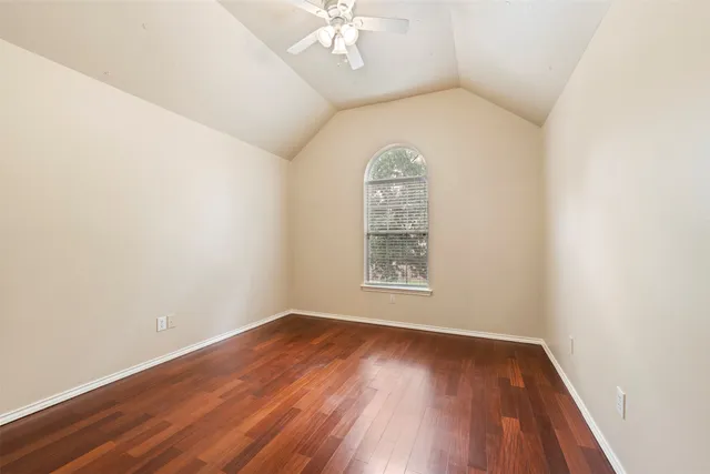 an empty room with wooden floor chandelier fan and windows