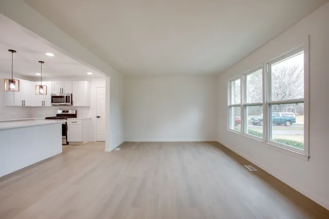 a view of an empty room with a window and wooden floor