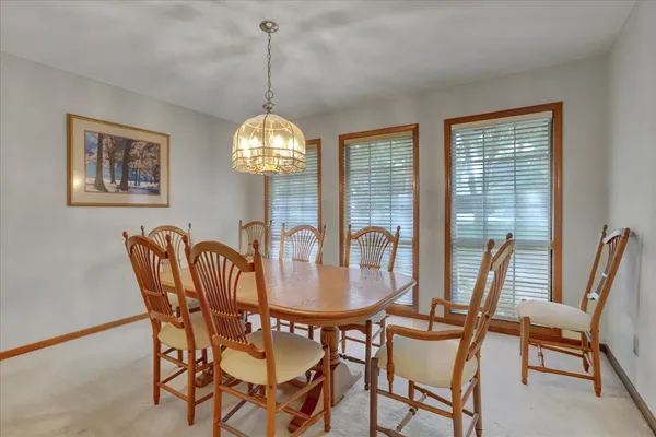 a kitchen with stainless steel appliances granite countertop a dining table chairs refrigerator and sink