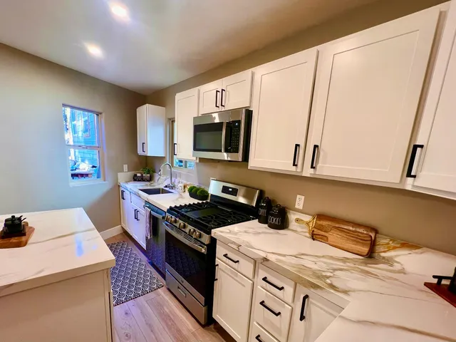a view of a livingroom with a chandelier fan and wooden floor