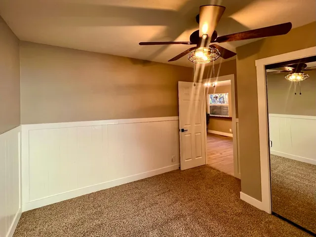 a view of empty room with wooden floor and fan