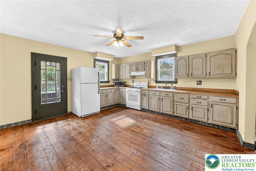 202 Main Street Portland, PA 18343 - Photo 12 of 40 a kitchen with stainless steel appliances granite countertop a refrigerator a sink dishwasher a stove with wooden floor and cabinets