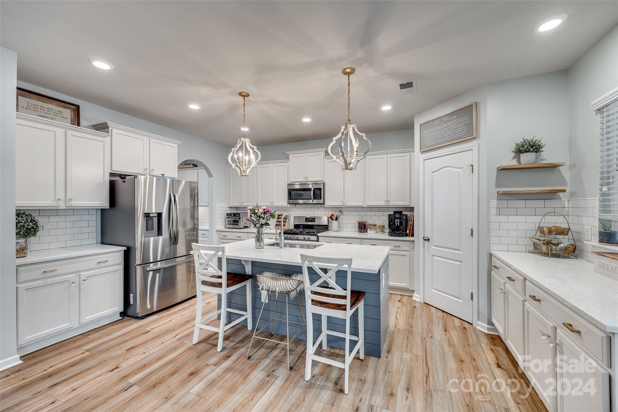 2251 Elmview Lane Fort Mill, SC 29715 - Photo 6 of 46 a kitchen with stainless steel appliances kitchen island granite countertop a refrigerator a stove a sink a dining table and chairs with wooden floor