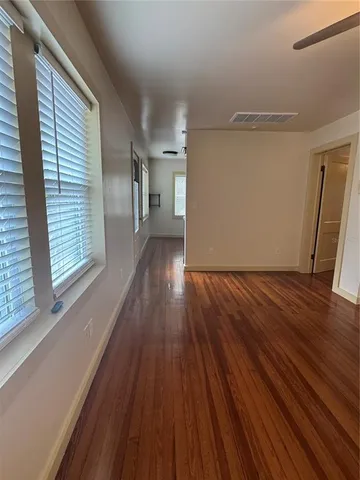 a view of empty room with wooden floor and fan